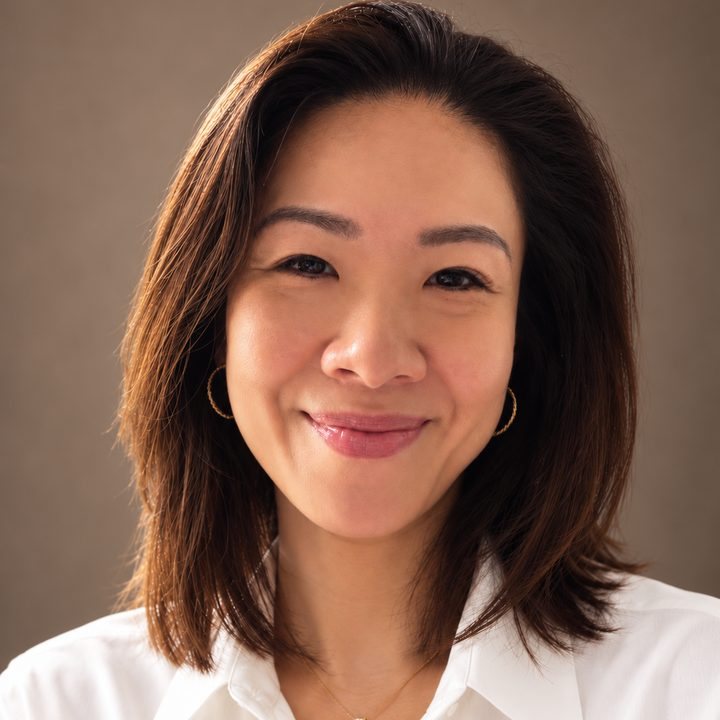 Portrait of Peggy Santosa, smiling, in a white shirt.